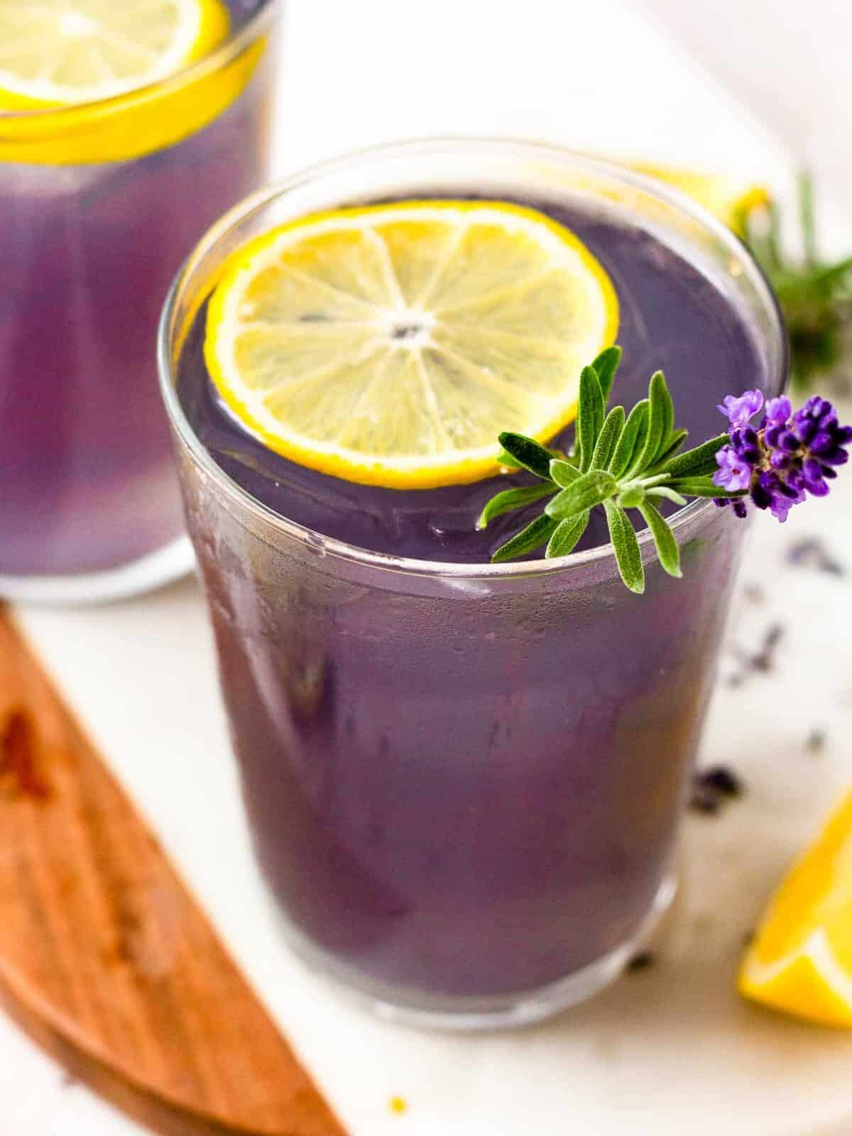 glass of lavender lemonade with a slice of lemon and lavender as garnish