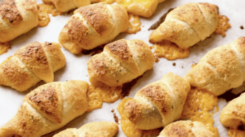 baked cheesy pigs in a blanket on a baking sheet.