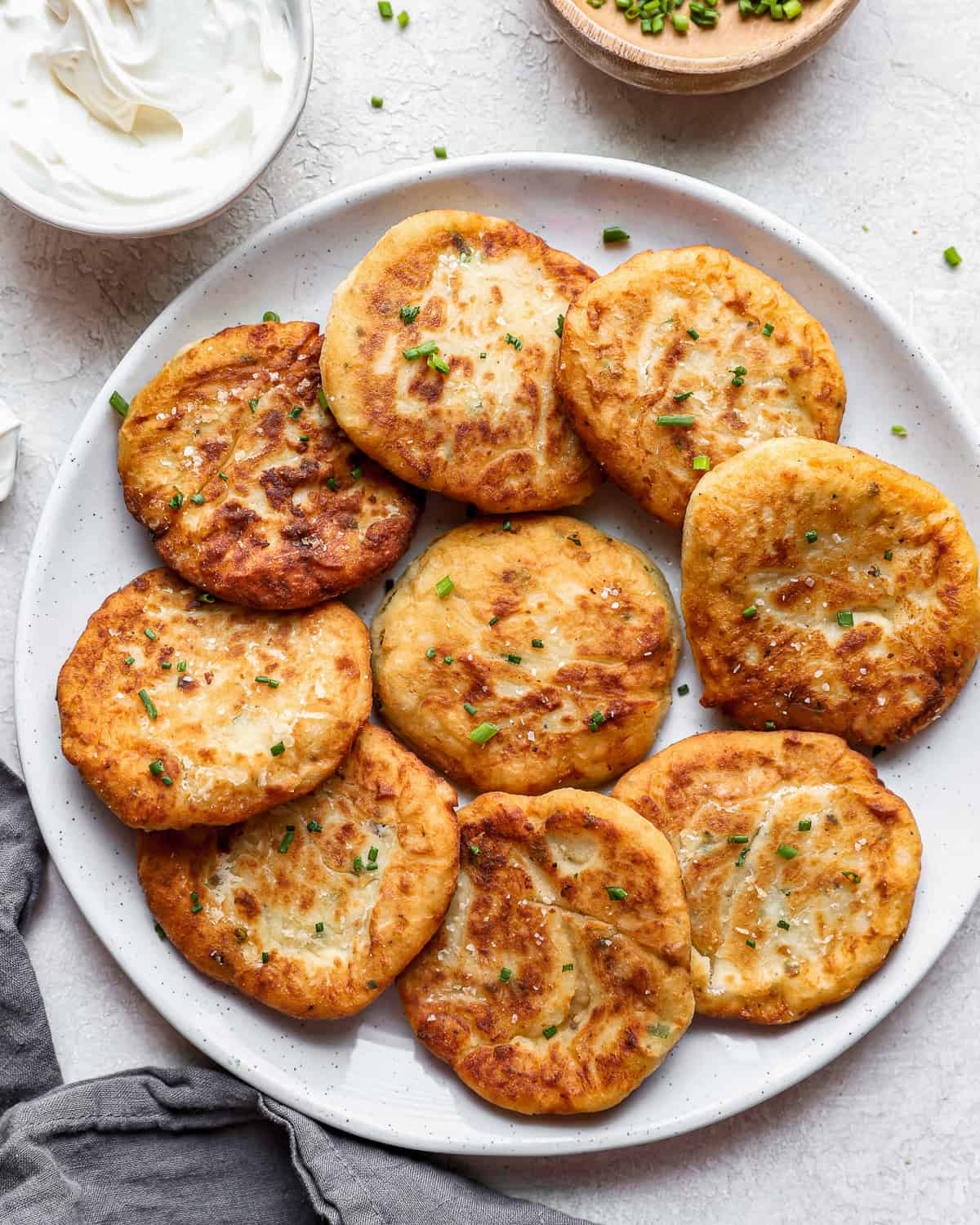 potato pancakes on a plate with sour cream and chives.