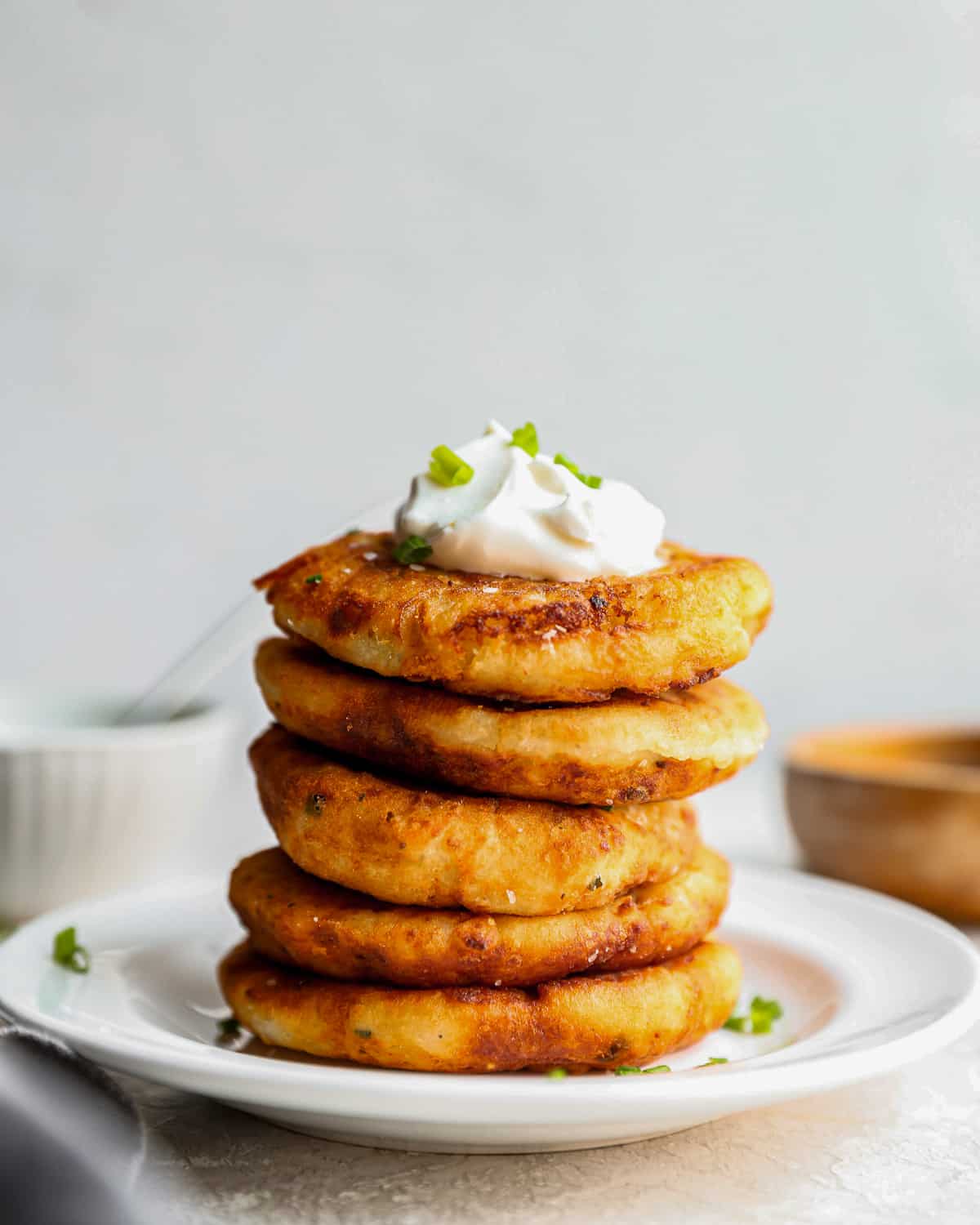 a stack of mashed potato pancakes topped with sour cream and chives.