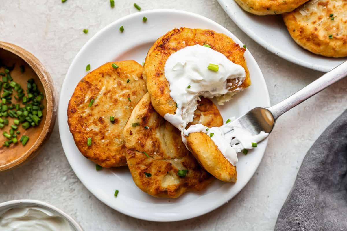 potato fritters with sour cream on a plate.