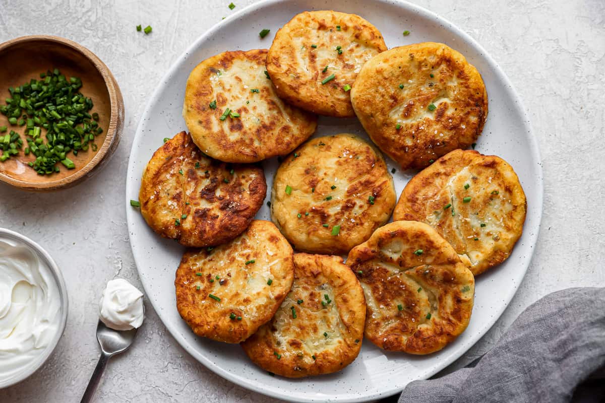 pancakes on a plate with sour cream and parsley.