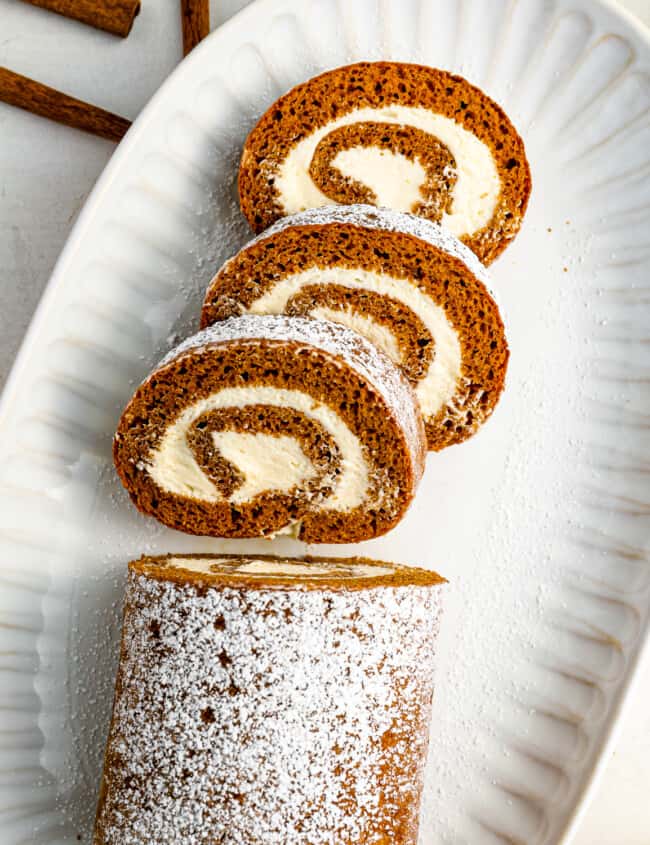 a cinnamon roll with powdered sugar on a white plate.