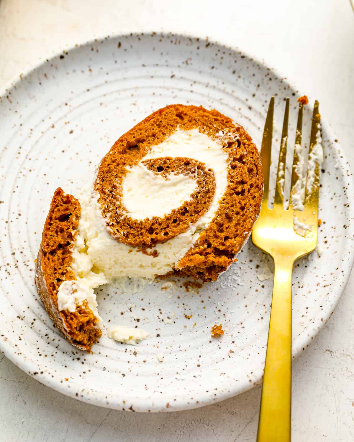 a slice of pumpkin cake roll on a plate with a fork.
