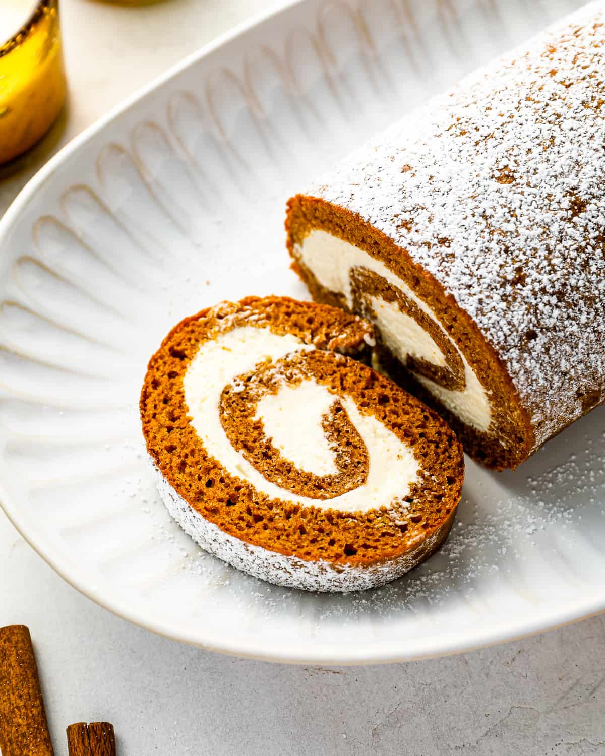 a slice of pumpkin roll with powdered sugar on a plate.