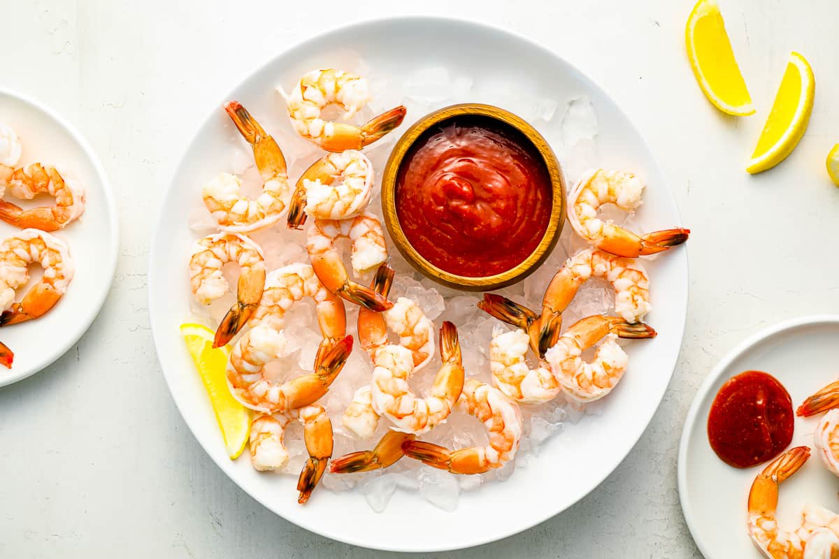 shrimp on ice with sauce on a white plate.