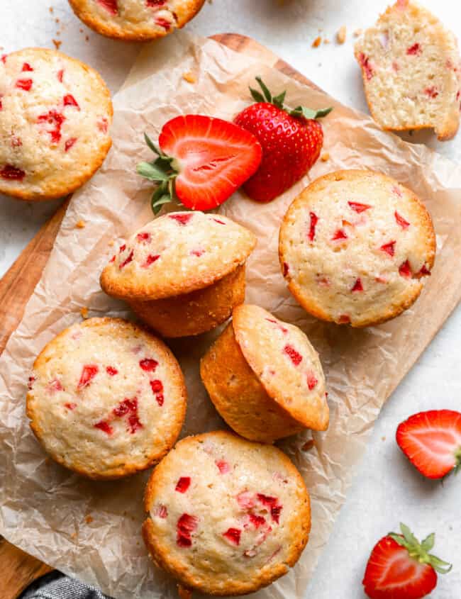 strawberry muffins on a cutting board with strawberries.