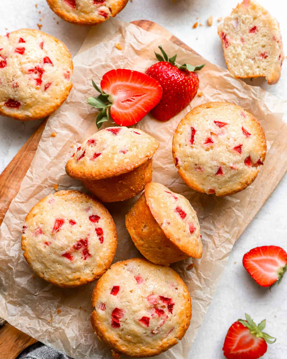 strawberry muffins on a cutting board with strawberries.