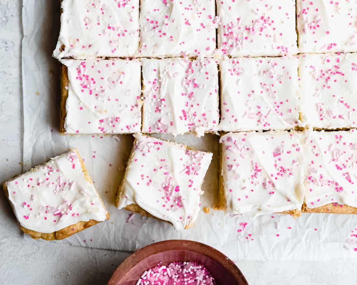 sugar cookies bars topped with icing and pink sprinkles.