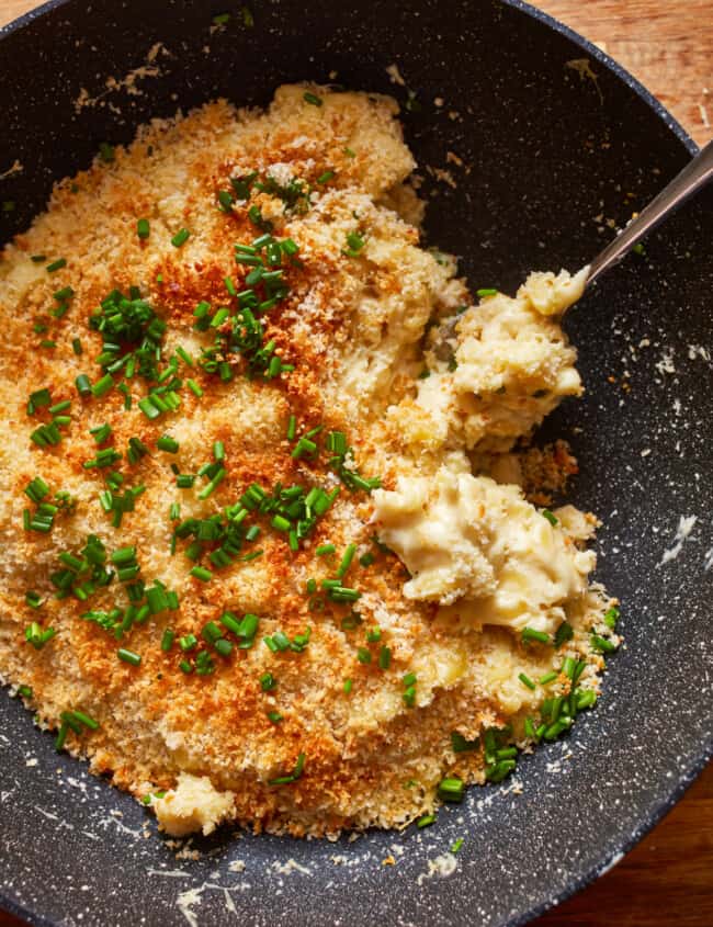 a bowl of mashed potatoes with cheese and parsley.