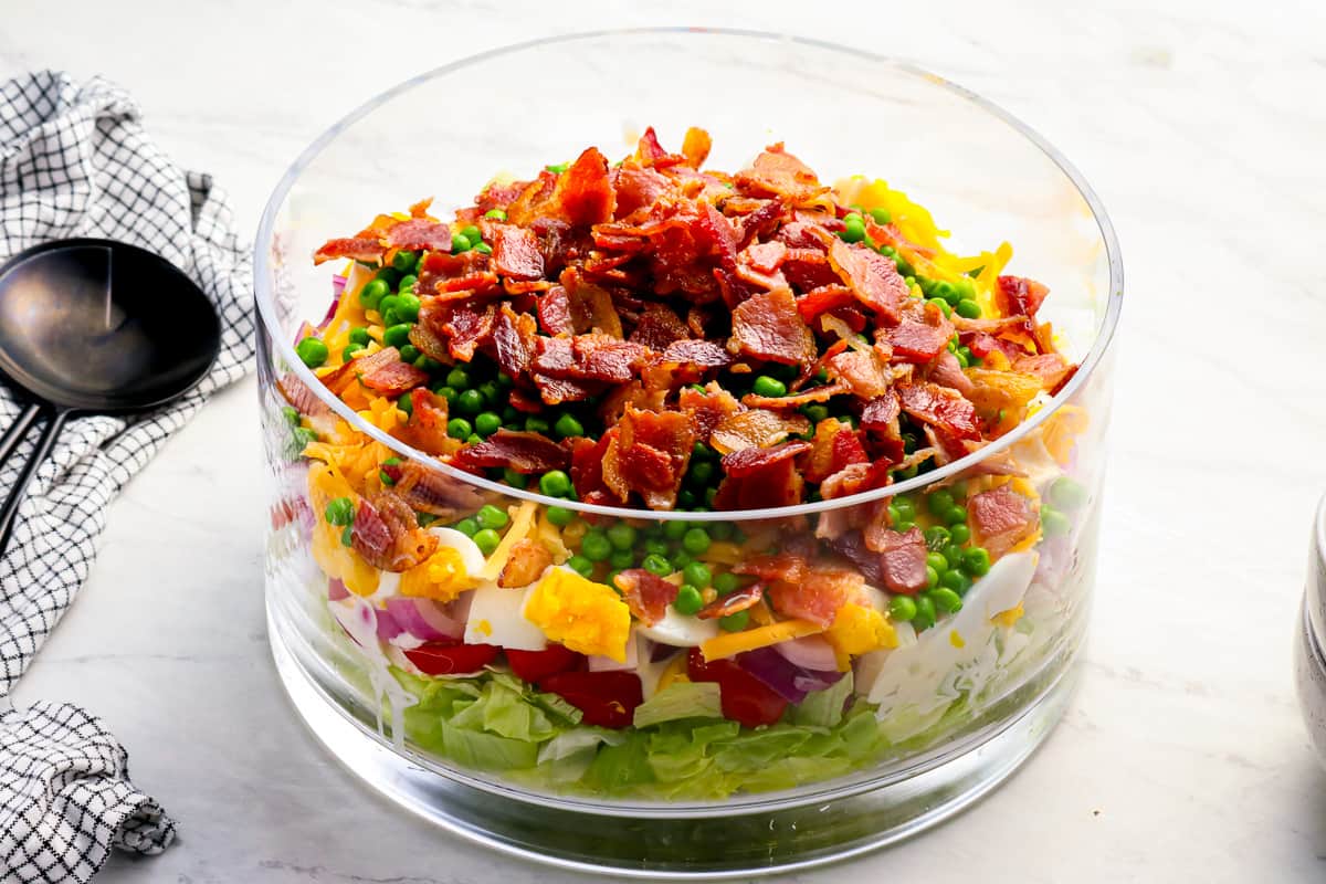 a large salad with layers of ingredients, in a large glass dish.