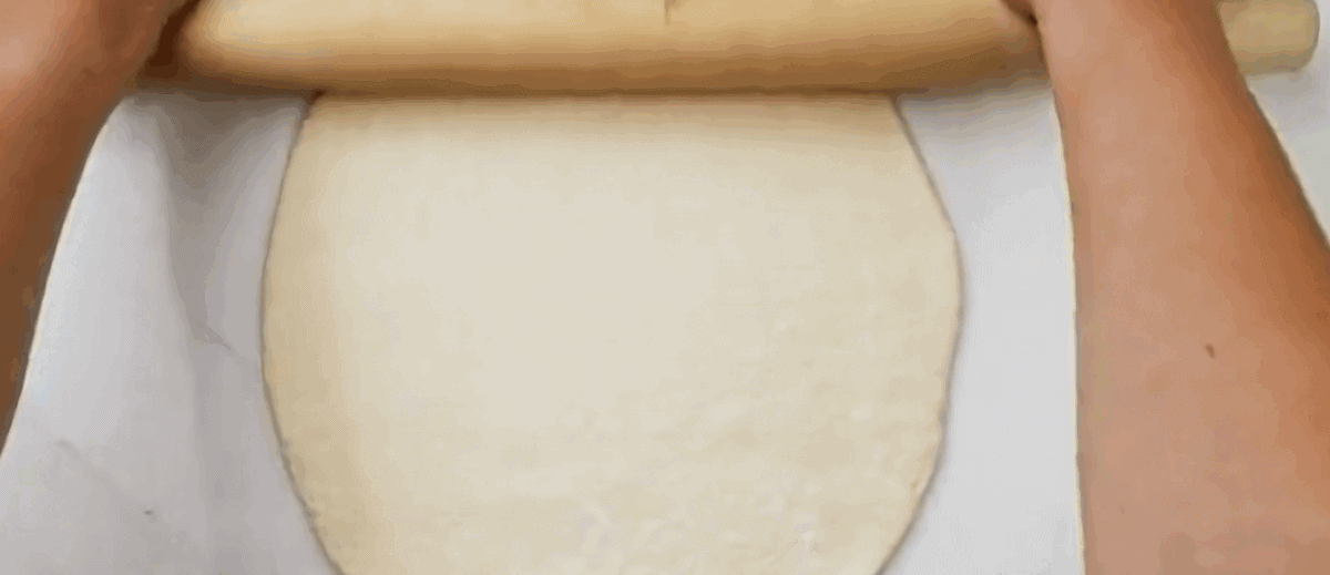 Rolling out pizza dough with a rolling pin.