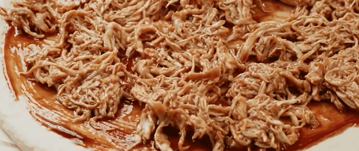 Adding chicken to the bbq sauce topped pizza dough.