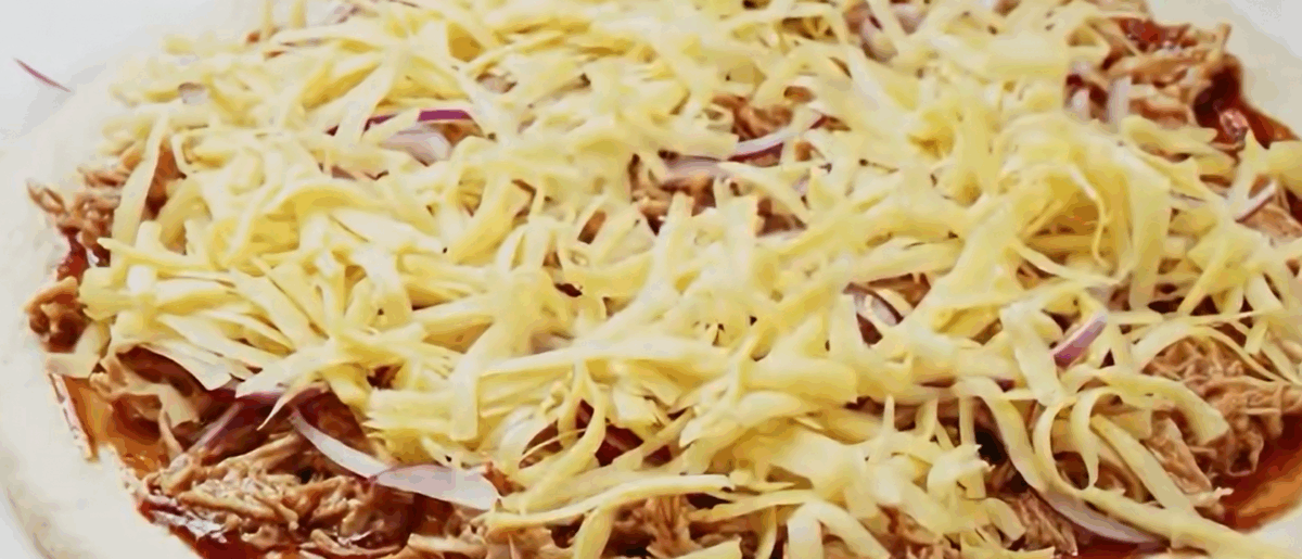 Adding cheese and onion to the pizza.