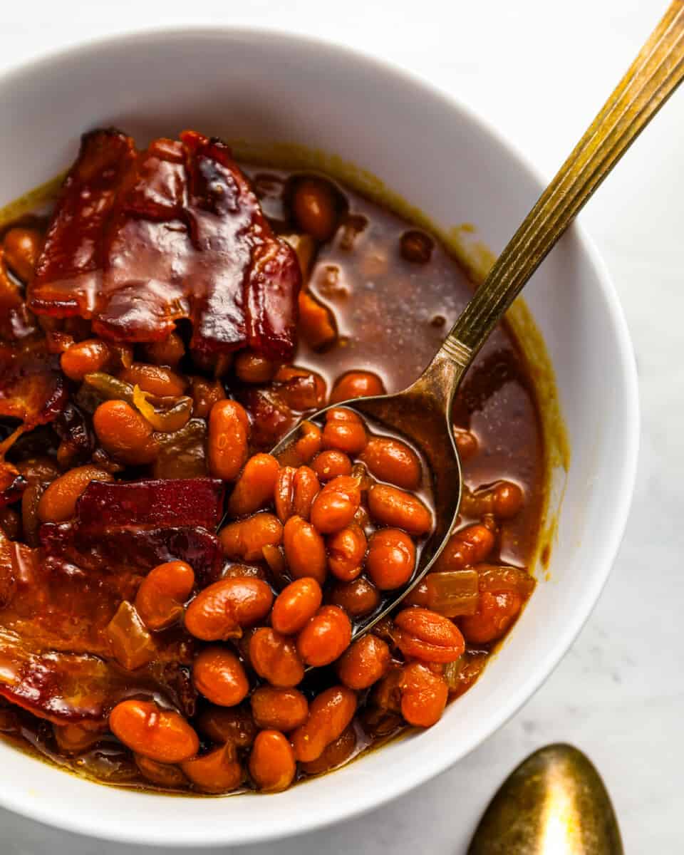 A bowl of beans and bacon in a white bowl.