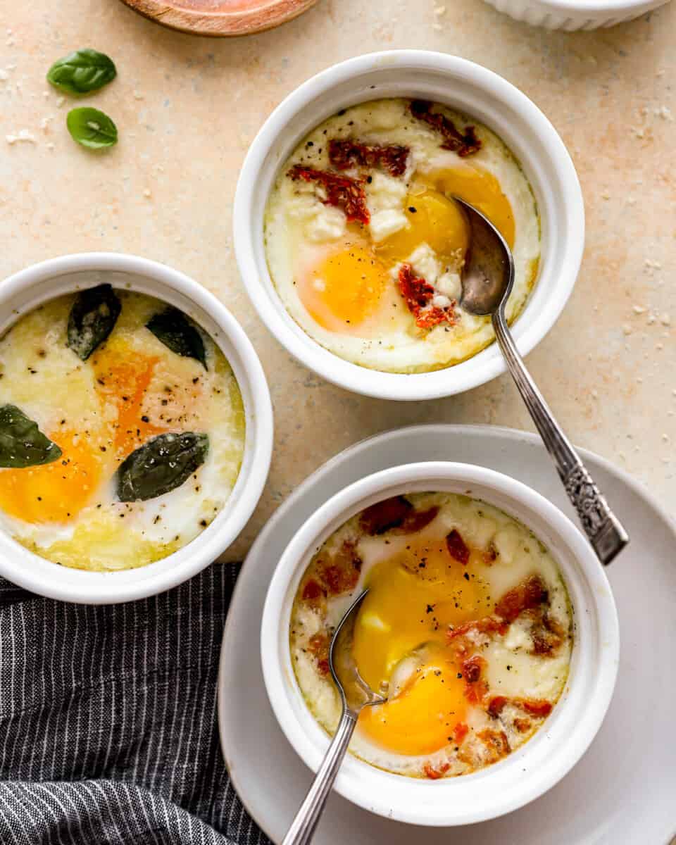 baked eggs in ramekin cups, each with different toppings.
