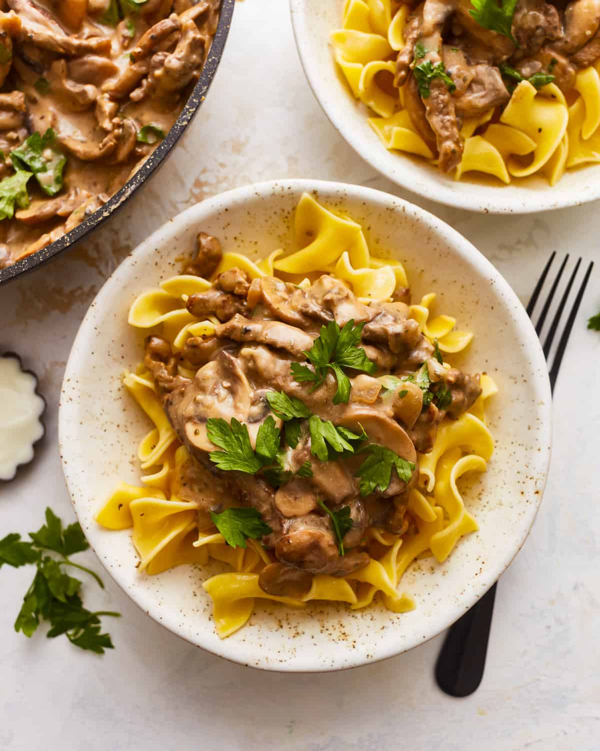 Two bowls of swedish stroganoff with mushrooms and parsley.