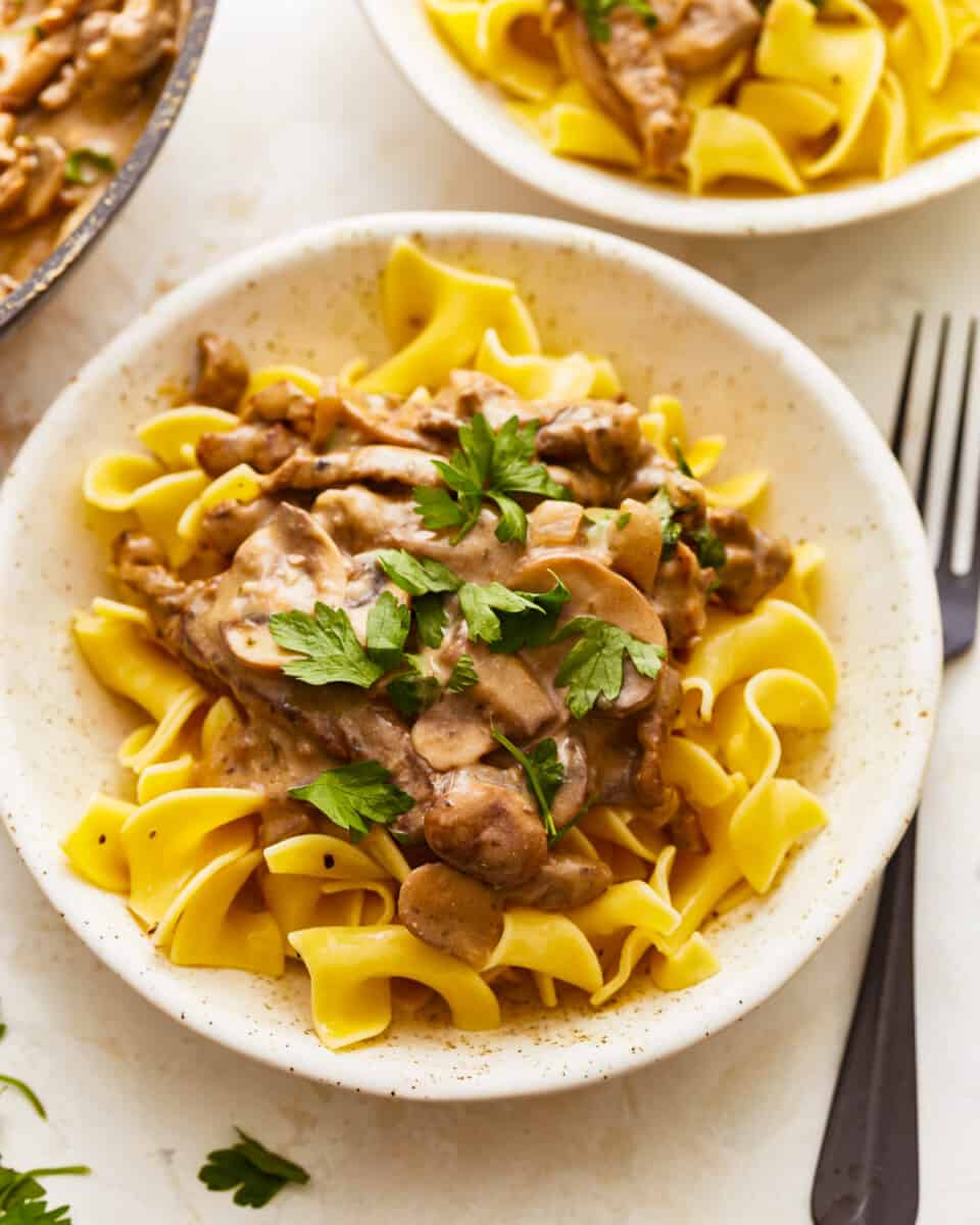Beef stroganoff in a white bowl with parsley.