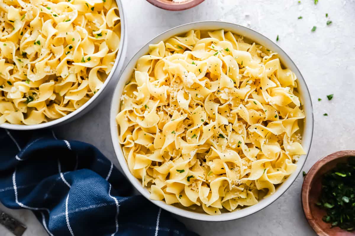 bowls of buttered noodles on a table.