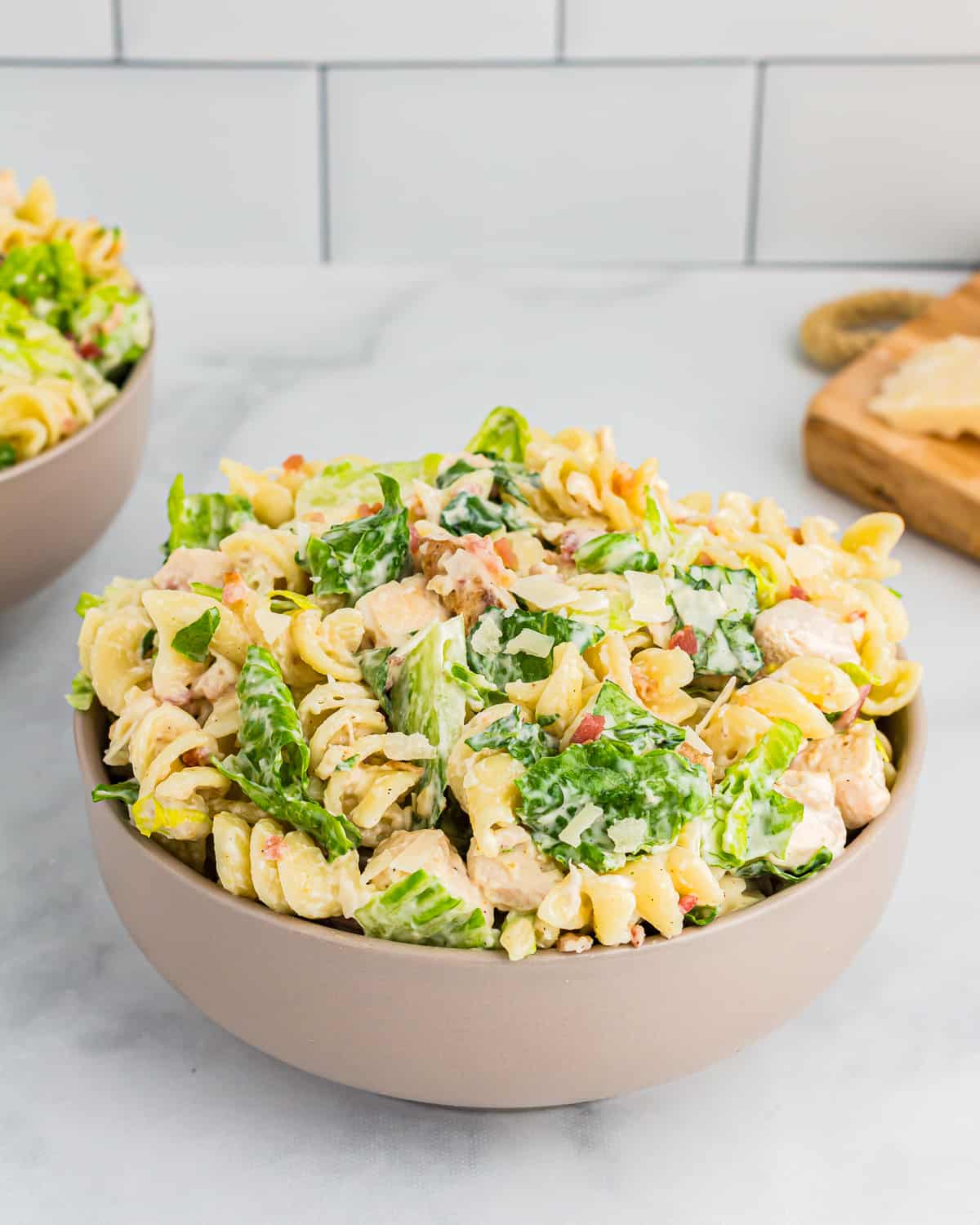 Two bowls of pasta salad on a marble counter.