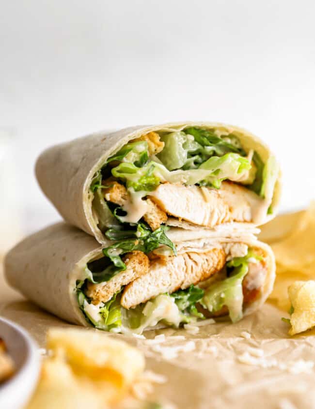A chicken burrito with lettuce and chips.