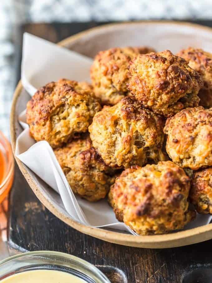This classic Sausage Balls recipe is savory, cheesy, and tasty! These Bisquick sausage balls are the perfect appetizer for holidays or game day. Serve them with apricot sweet chili dipping sauce! sausage balls arranged in a bowl