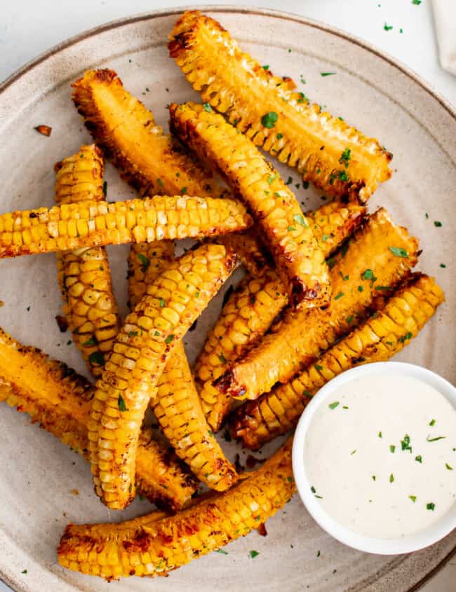 Corn on the cob served with a flavorful dipping sauce on a plate.
