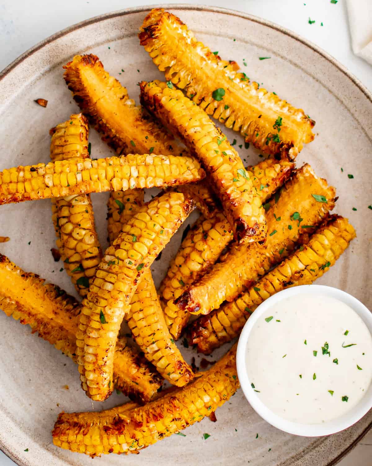 corn ribs served with a flavorful dipping sauce on a plate.