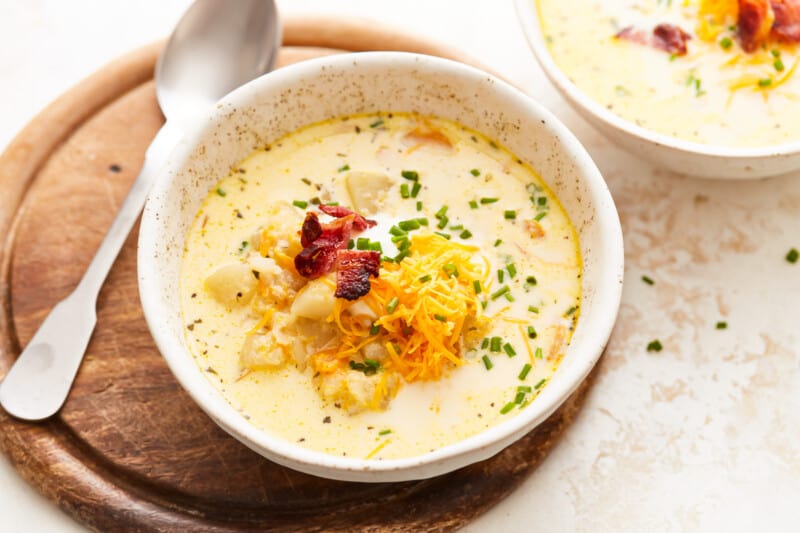 Two bowls of chowder with bacon and cheese.