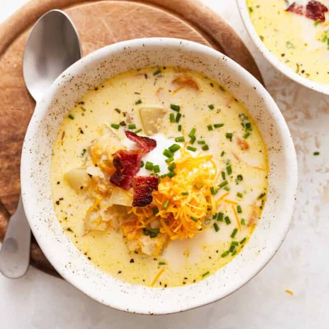 Two bowls of chowder with cheese and bacon.