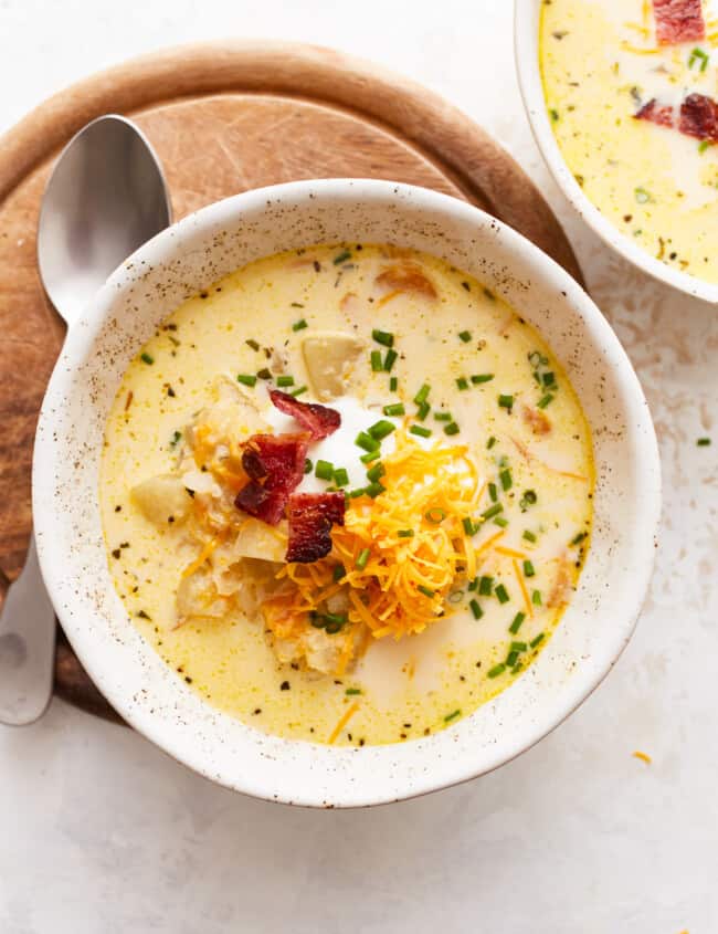 Two bowls of chowder with cheese and bacon.