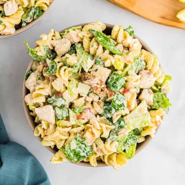 A bowl of pasta salad with chicken and lemon.