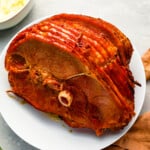 A roasted ham on a white plate.