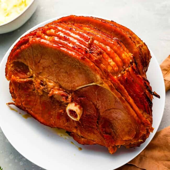 A roasted ham on a white plate.