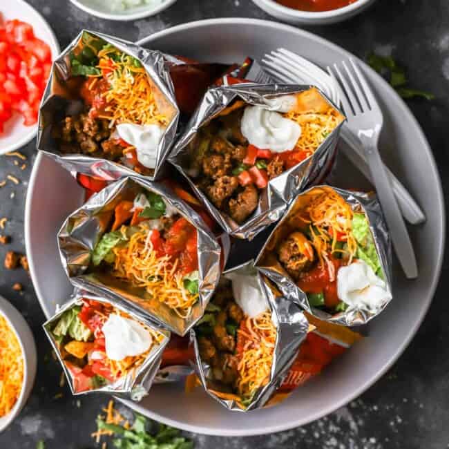 Mexican burritos wrapped in foil on a plate.