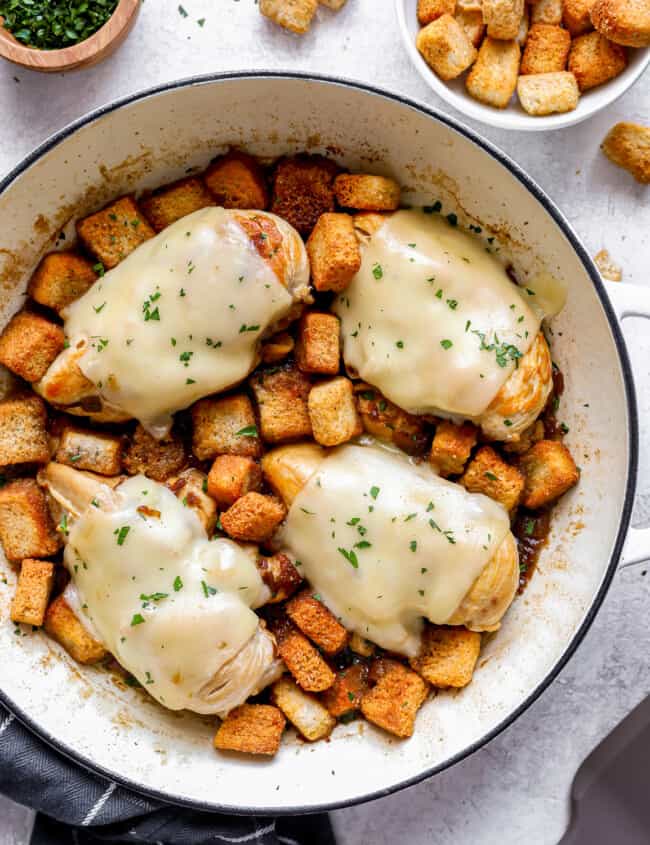 Chicken breasts in a skillet with croutons.