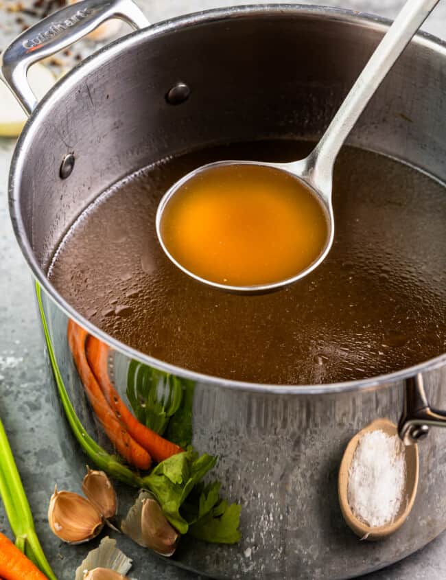 Broth in a pot with carrots and onions.