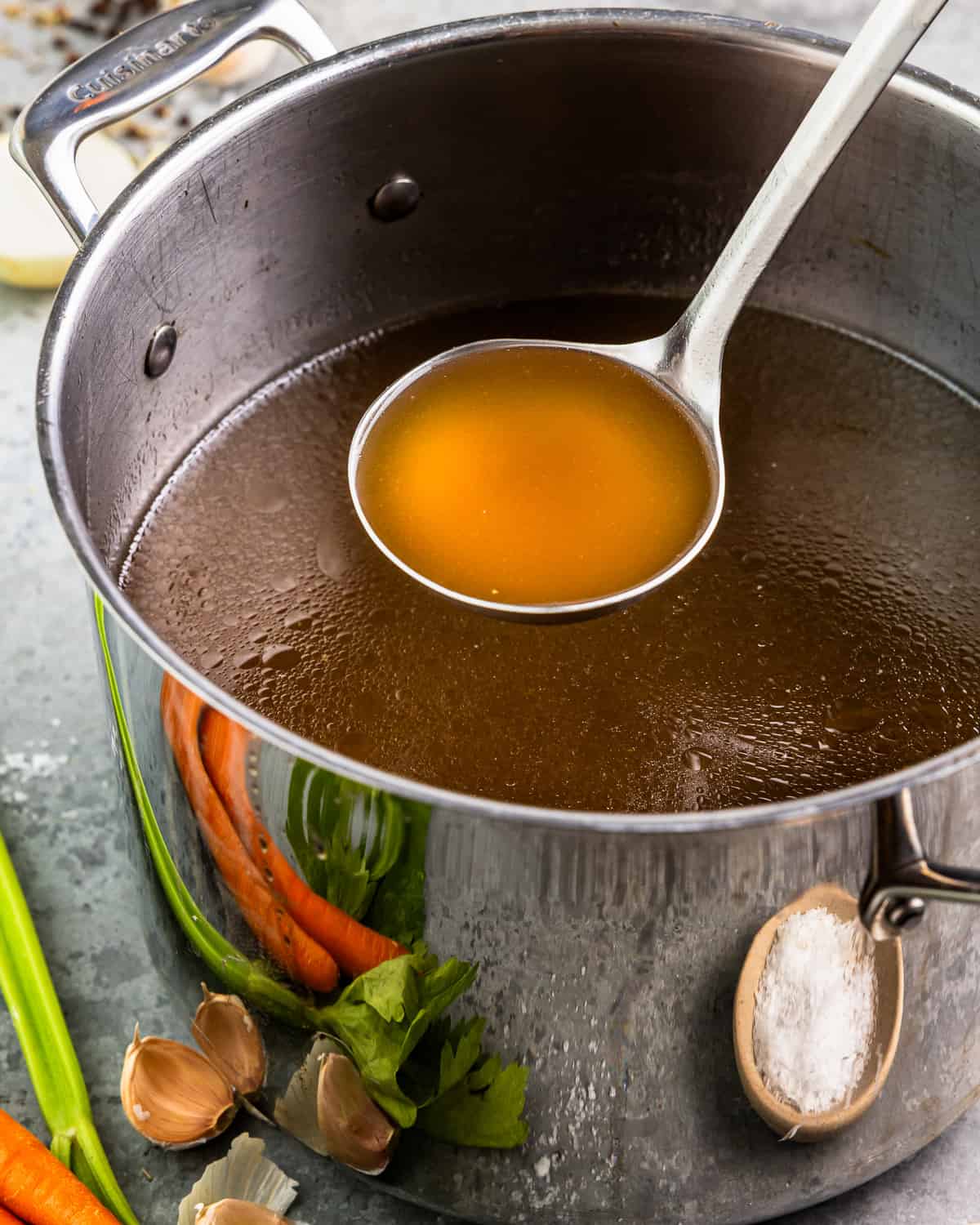 Broth in a pot with carrots and onions.
