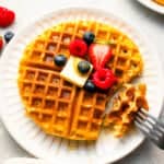 A plate of waffles with berries and a fork.