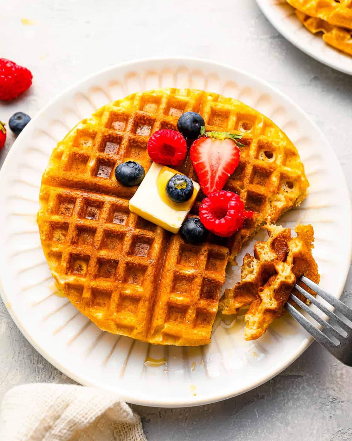 A plate of homemade waffles with berries and a fork.
