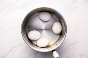 Three eggs in a pan on a marble surface.