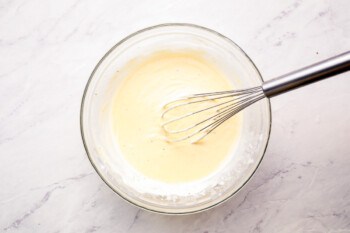 A whisk in a bowl of batter.