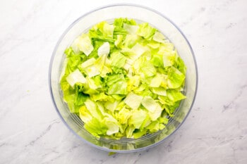 Shredded lettuce in a bowl on a marble surface.