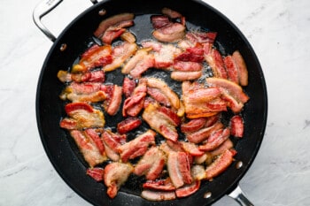 Bacon in a skillet on a marble countertop.