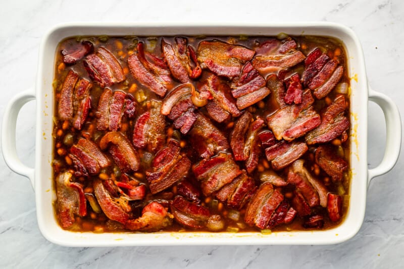 Bacon and beans in a white baking dish.