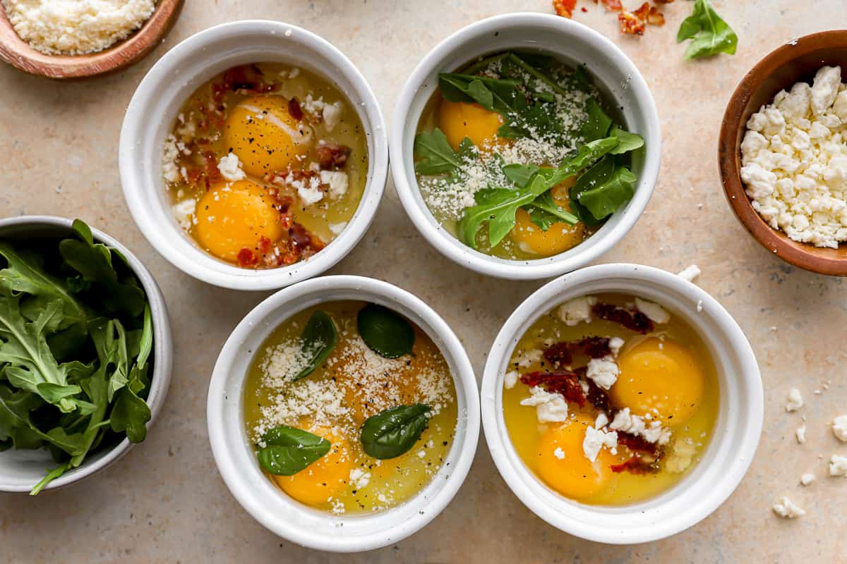 Four bowls filled with eggs, spinach, and herbs.