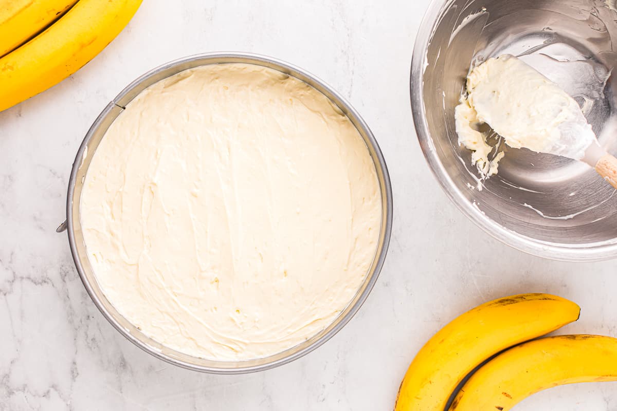 A bowl of icing and bananas next to a mixing bowl.