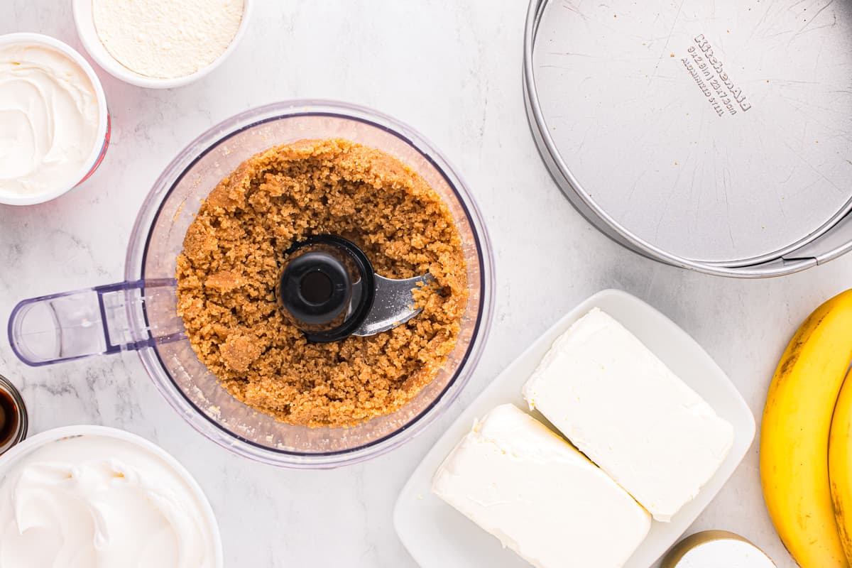 A food processor with bananas, whipped cream, and other ingredients.