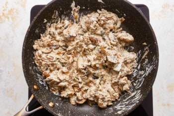 A frying pan with a mixture of nuts and cheese.