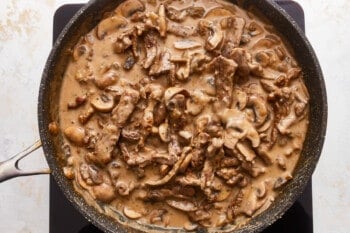 A skillet full of beef and mushrooms in a sauce.